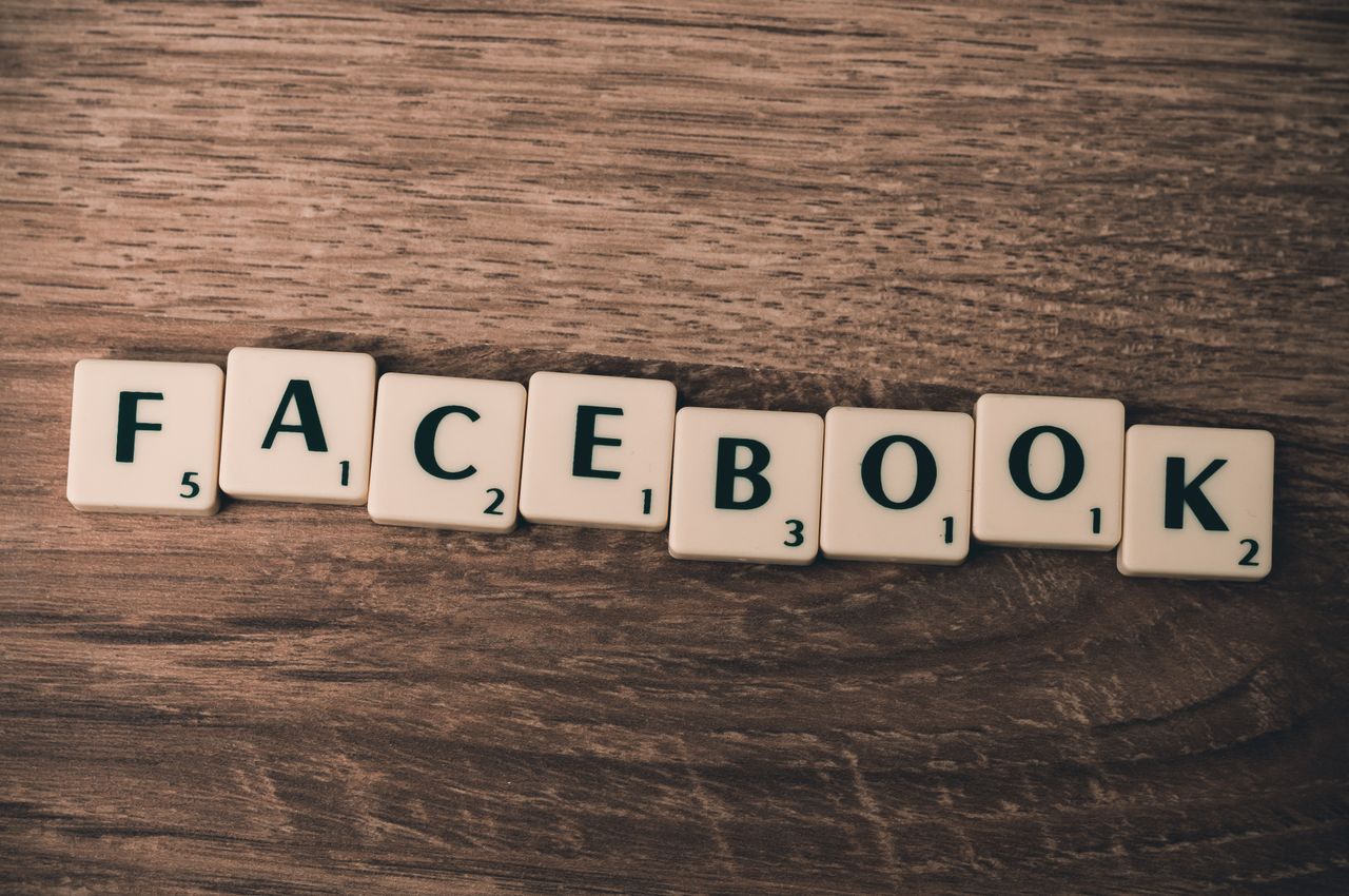 Des lettres de Scrabble formant Facebook sur un fond en bois, illustrant les réseaux sociaux.